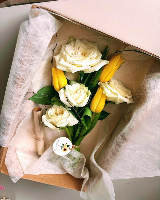 Aranjament floral în cutie kraft cu trandafiri albi și lalele galbene